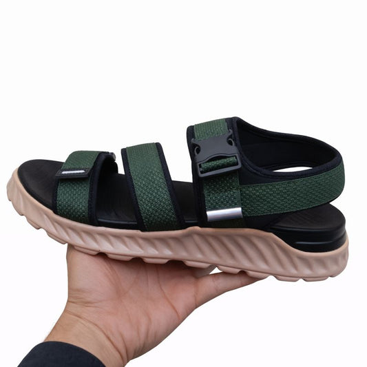Green and black sandals held in a hand right side on a white background