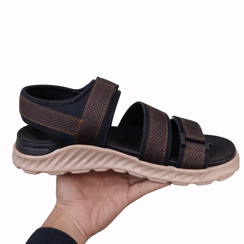 Black and brown sandal with thick sole left side view held by a hand on a white background