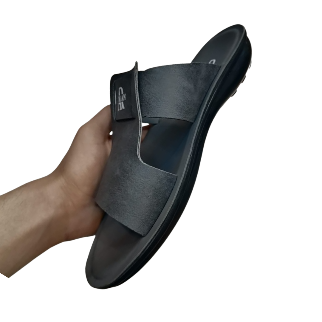 Black slipper for men left view being held by a hand on a white background