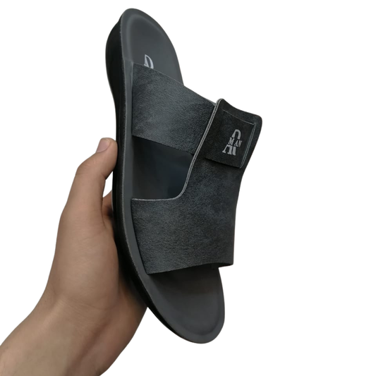 Black slipper for men held by a hand on a white background