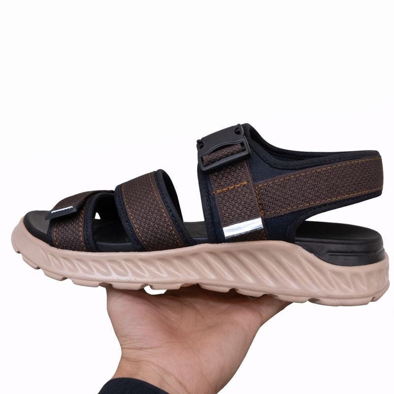 Brown and black sandal right side view held in a hand on a white background