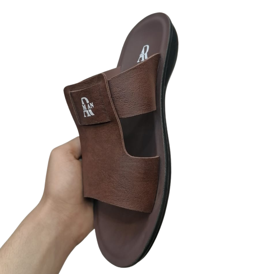 Brown slipper for men held by a hand on a white background