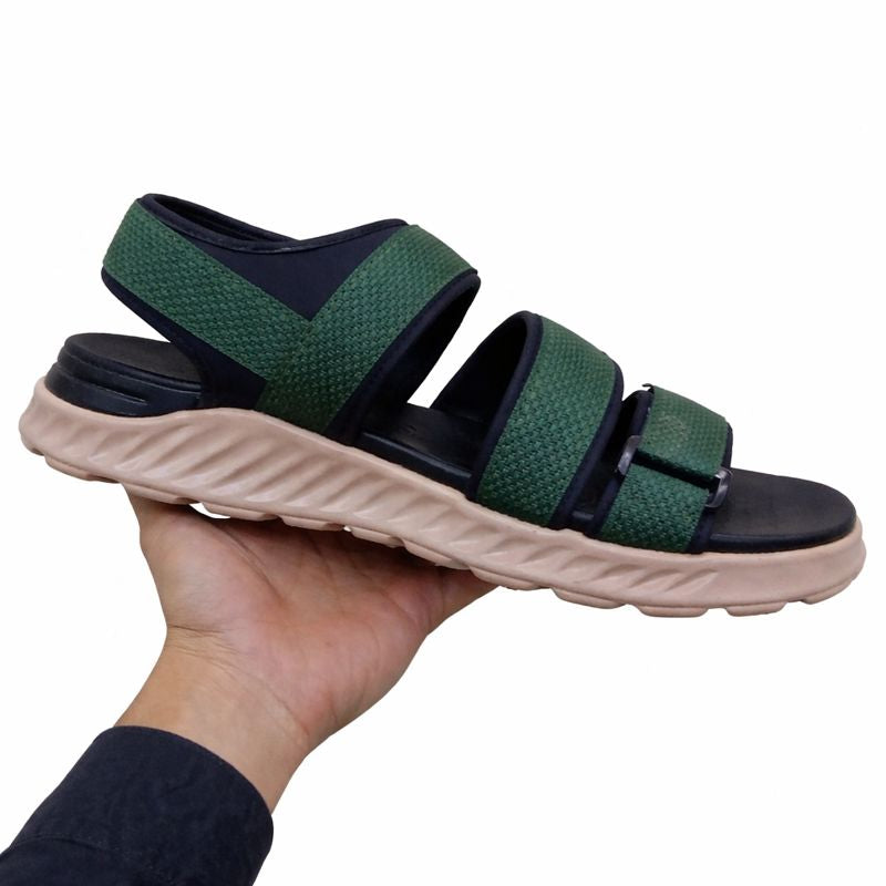 Green and black sandal left view held in a hand against a white background