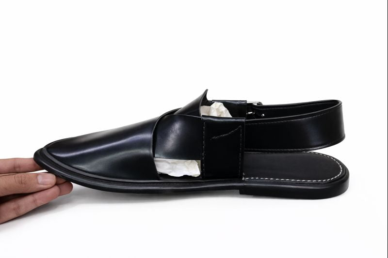 Peshawari Chappal Black sandal left view with a white sole held by a hand on a white background 