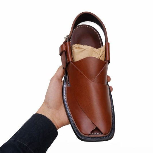 Peshawari Chappal Brown sandal held in a hand against a white background